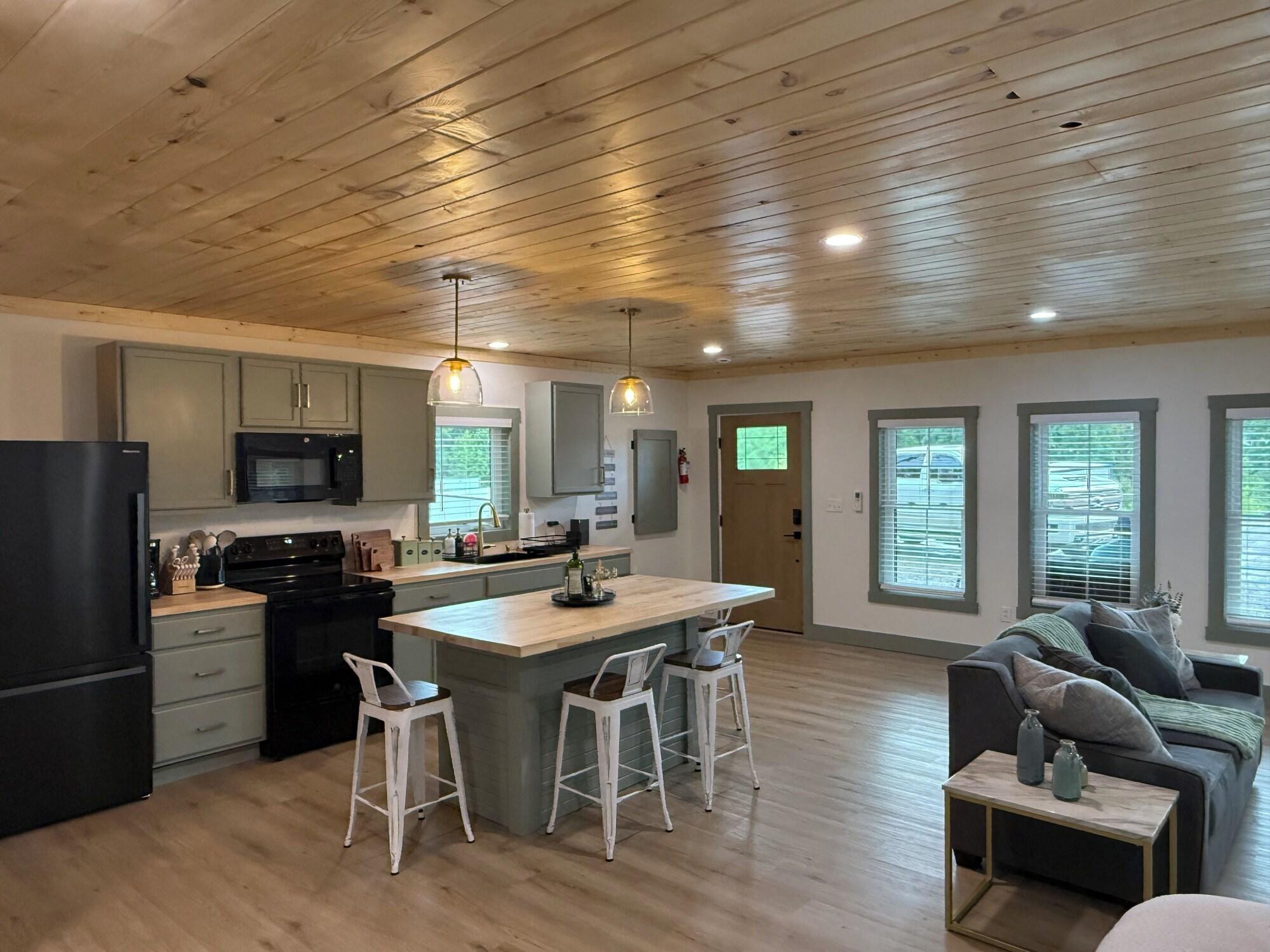 Open studio living area and kitchen with island seating and pine ceiling at Hideaway at Wolf Creek