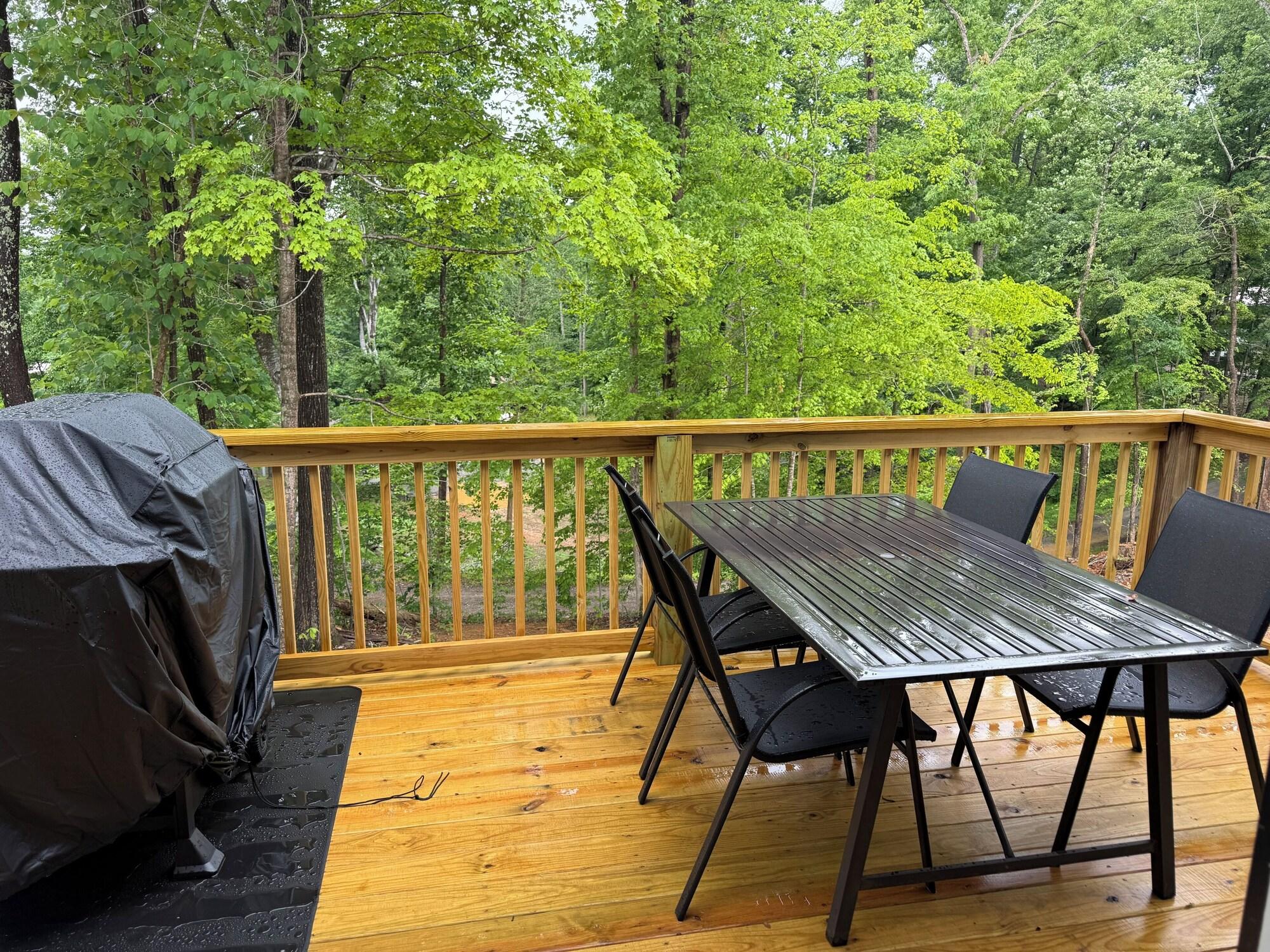 Back deck with dining table and grill overlooking the woods at Hideaway at Wolf Creek